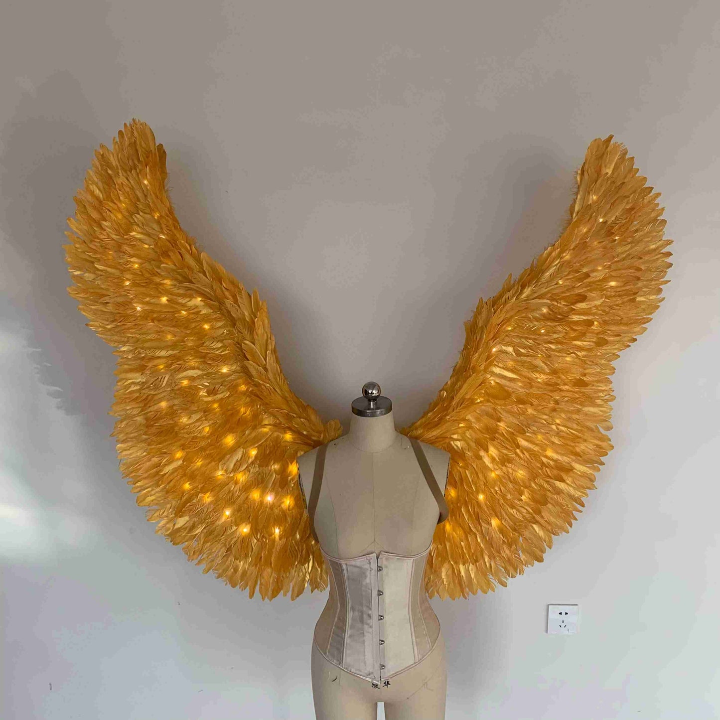 Our gold color angel wings from the front. Made from goose feathers with LED lights inside. Wings for angel costume. Suitable for photoshoots.