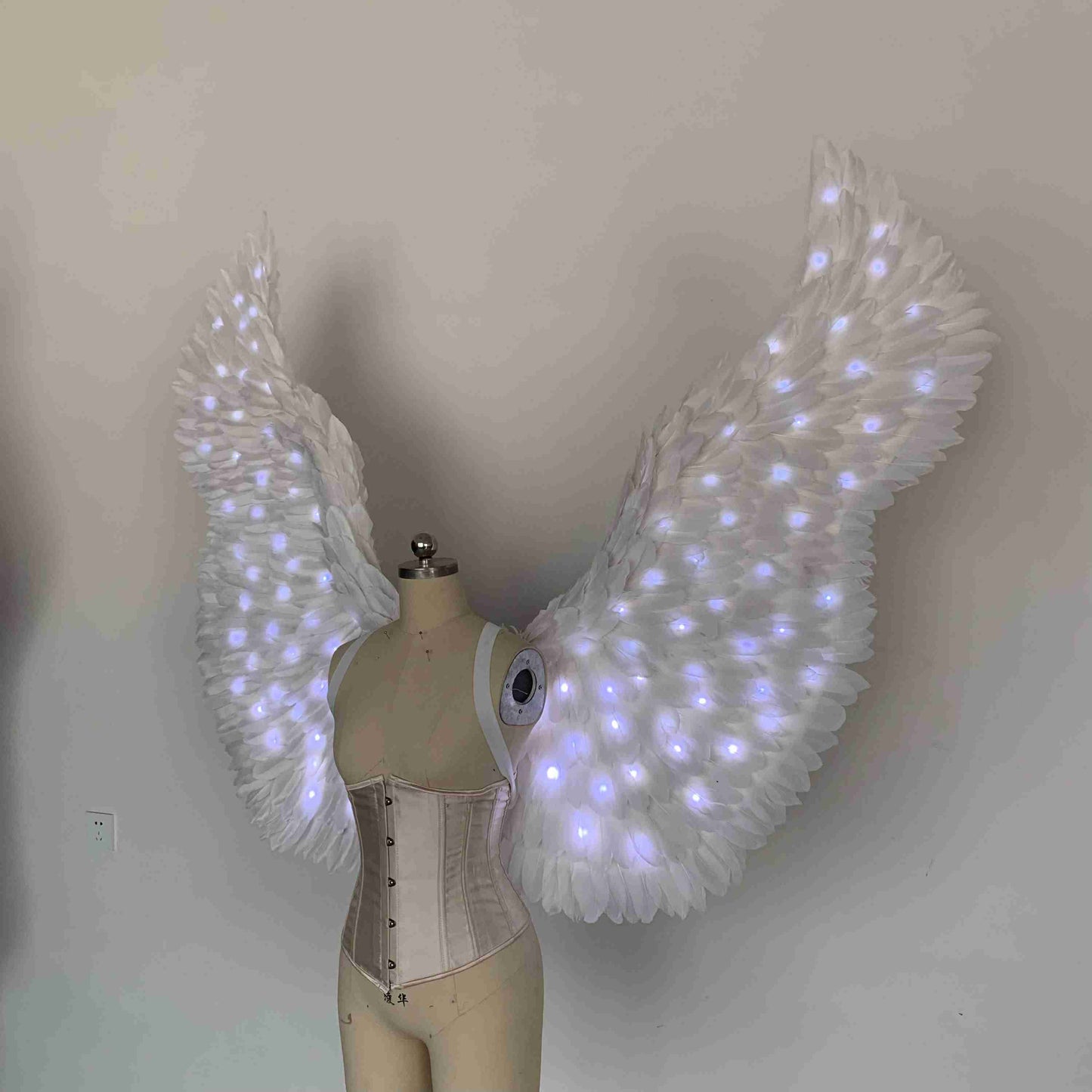 Our white color angel wings from the left side. Made from goose feathers with LED lights inside. Wings for angel costume. Suitable for photoshoots.